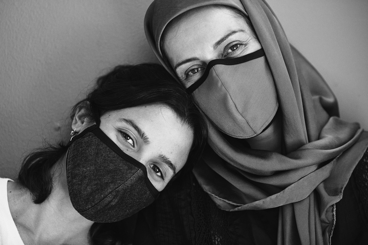 Two women wearing masks leaning into each other
